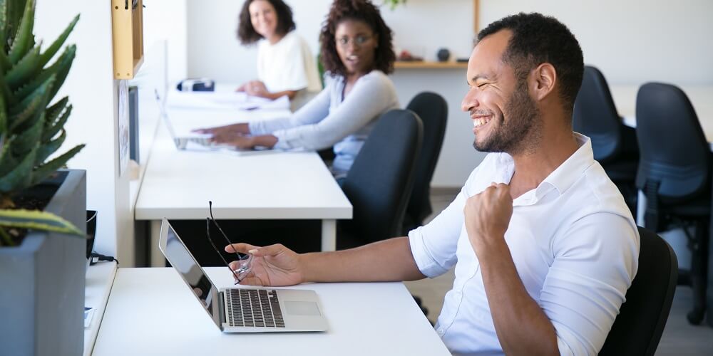 Empreendedor comemorando a alta taxa de tráfego no site de sua empresa, pois soube como atrair clientes para seu site por meio do marketing digital