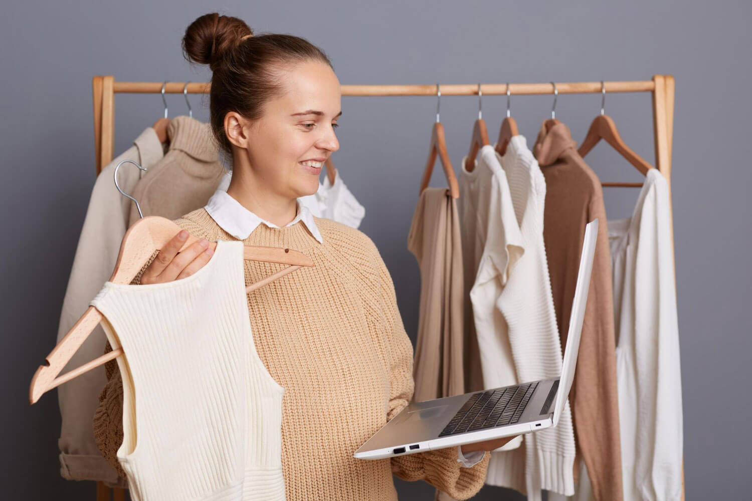 mulher segurando um notebook e peça de roupa se preparando para iniciar um planejamento de marketing para loja de roupas