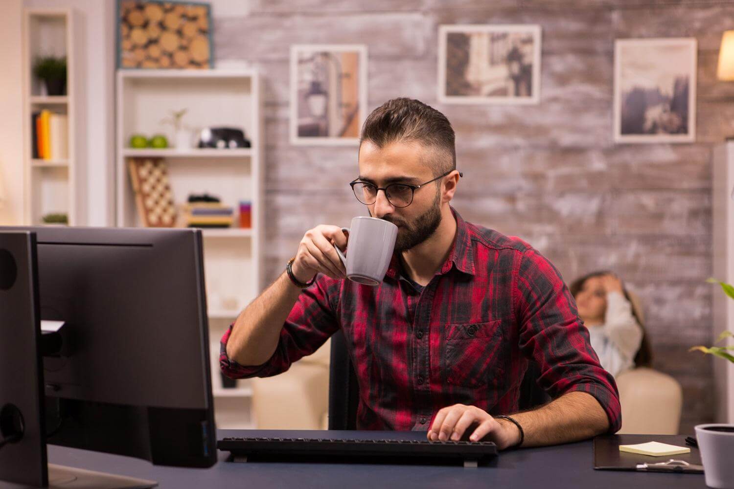 Pessoa em seu escritório bebendo café enquanto realiza um estudo de análise competitiva de SEO.