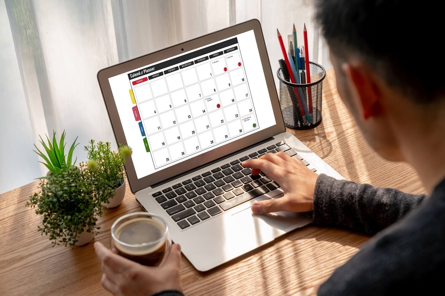 Dono de uma empresa visualizando um calendário em um notebook para preparar sua equipe de marketing e vender mais em datas sazonais.