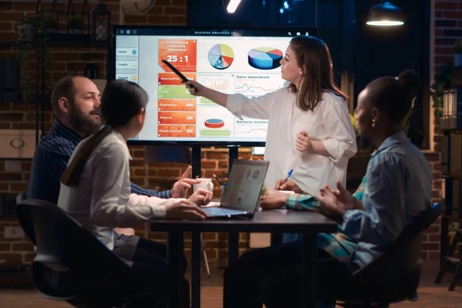 Grupo de pessoas sentadas em uma mesa realizando um plano de estratégia para a geração de leads em uma grande empresa.