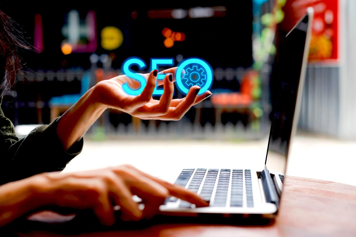 pessoa usando um notebook e segurando um pequeno holograma do SEO
